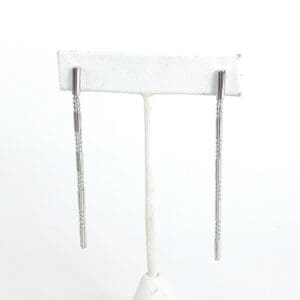 Silver dangle earrings on display stand.