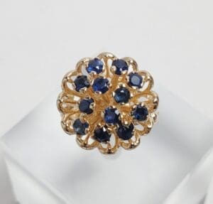 Gold ring with blue gemstones on display.