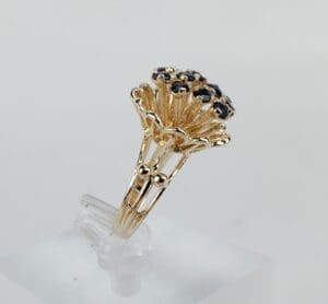 Gold ring with dark gemstone cluster design.