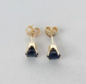 Gold earrings with dark blue gemstones.