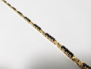 Gold bracelet with blue gemstones on display.