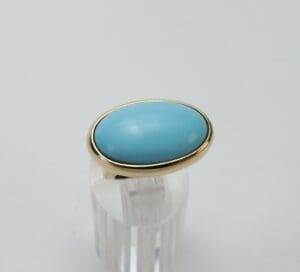 Gold ring with oval turquoise stone.