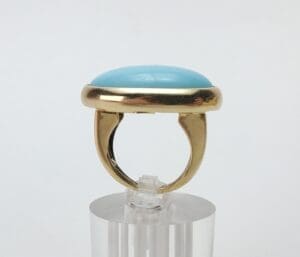 Gold ring with blue stone on stand.