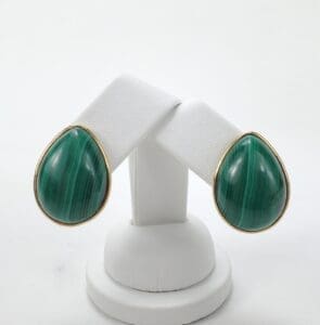 Green teardrop earrings on white stand.
