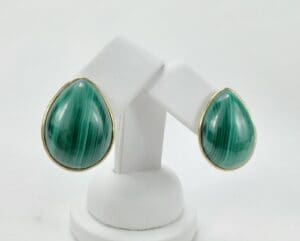 Green teardrop earrings on white stand.