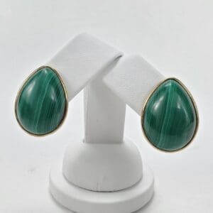 Green teardrop earrings on white stand.