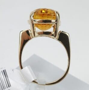 Gold ring with round orange gemstone.