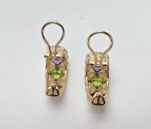 Gold earrings with purple and green stones.