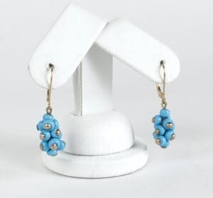 Blue beaded earrings on white stand.