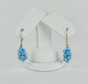 Blue beaded earrings on white display stand.
