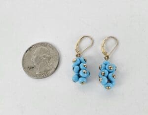 Blue bead earrings next to a quarter.