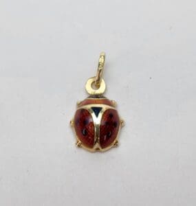 Ladybug pendant with gold loop on white.