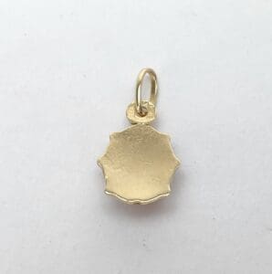 Gold pendant with scalloped edges on white.