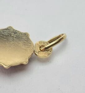 Gold pendant with loop on white background.