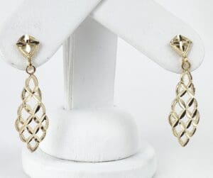 Gold lattice earrings on display stand.