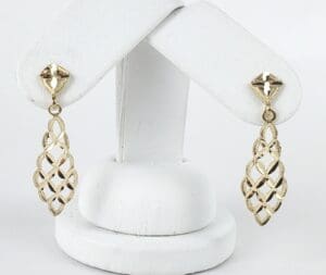 Gold lattice drop earrings on display stand.