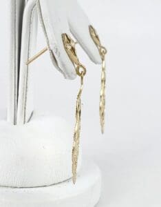 Gold dangling earrings on display stand.