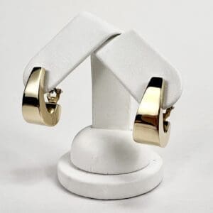 Gold hoop earrings on white stand.