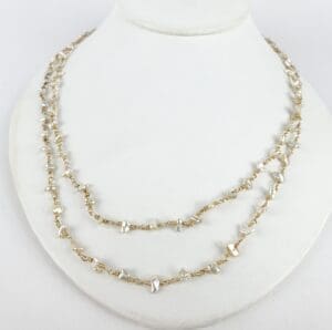 Gold and pearl necklace on display stand.