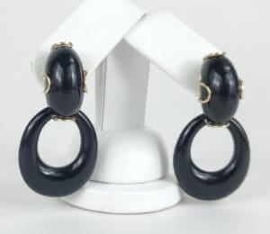 Black hoop earrings on white display stand.