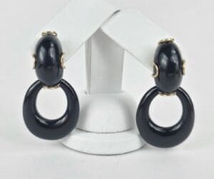 Black hoop earrings on white display stand.