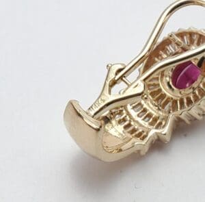 Gold pendant with pink gemstone detail.