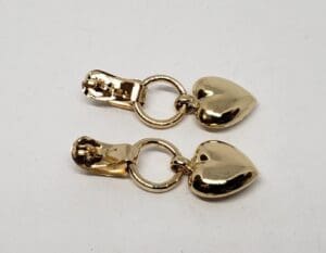 Gold heart-shaped zipper pulls on white background.