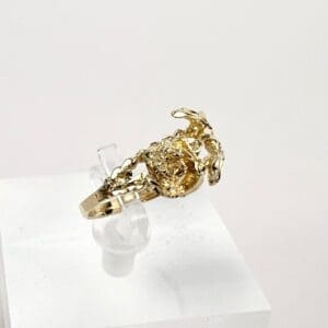 Gold scorpion ring on display stand.
