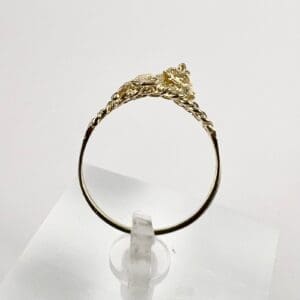 Gold ring with intricate design on stand.