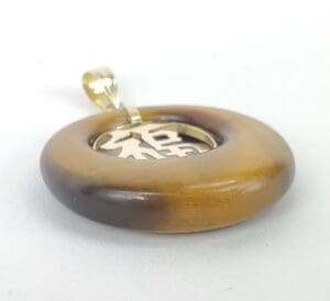Round pendant with metal symbol inside.