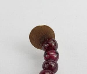 Red beaded earring with round gold backing.
