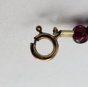 Gold clasp with red bead detail.