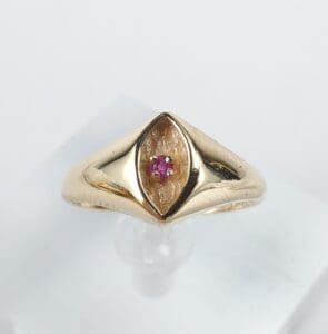 Gold ring with a small pink gemstone.