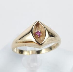 Gold ring with a small pink gemstone.
