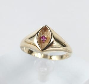 Gold ring with a small red gemstone.