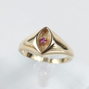 Gold ring with a small red gemstone.