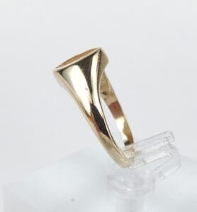 Gold ring with geometric design on stand.