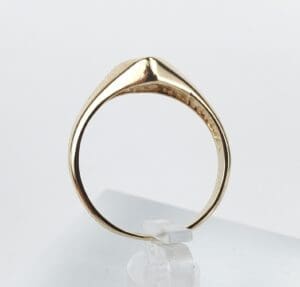 Gold ring displayed on a clear stand.