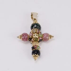 Intricate gemstone cross pendant on display.
