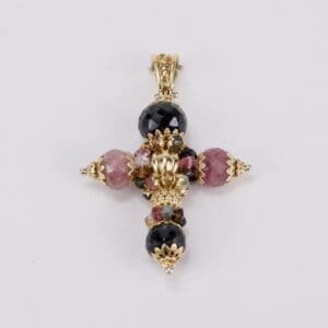 Gold cross pendant with colorful gemstones.