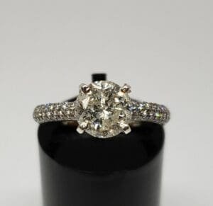 Diamond engagement ring on black stand.