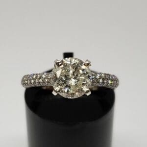 Diamond engagement ring on black stand.