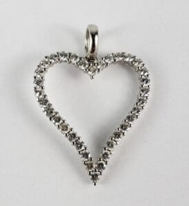 Heart-shaped diamond pendant on white background.