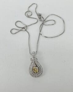 Silver necklace with a yellow gemstone pendant.