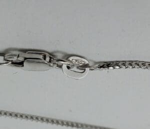 Silver chain clasp with hallmark detail.