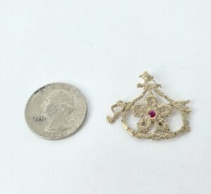 Quarter and ornate gold brooch with gemstone.