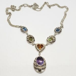 Silver necklace with colorful gemstone pendants.