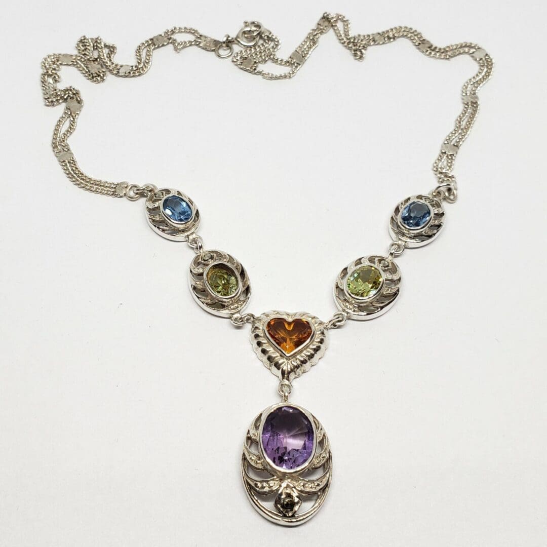 Silver necklace with colorful gemstone pendants.