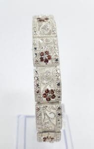 Ornate silver bracelet with red gemstones.