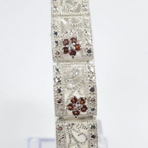 Ornate silver bracelet with red gemstones.